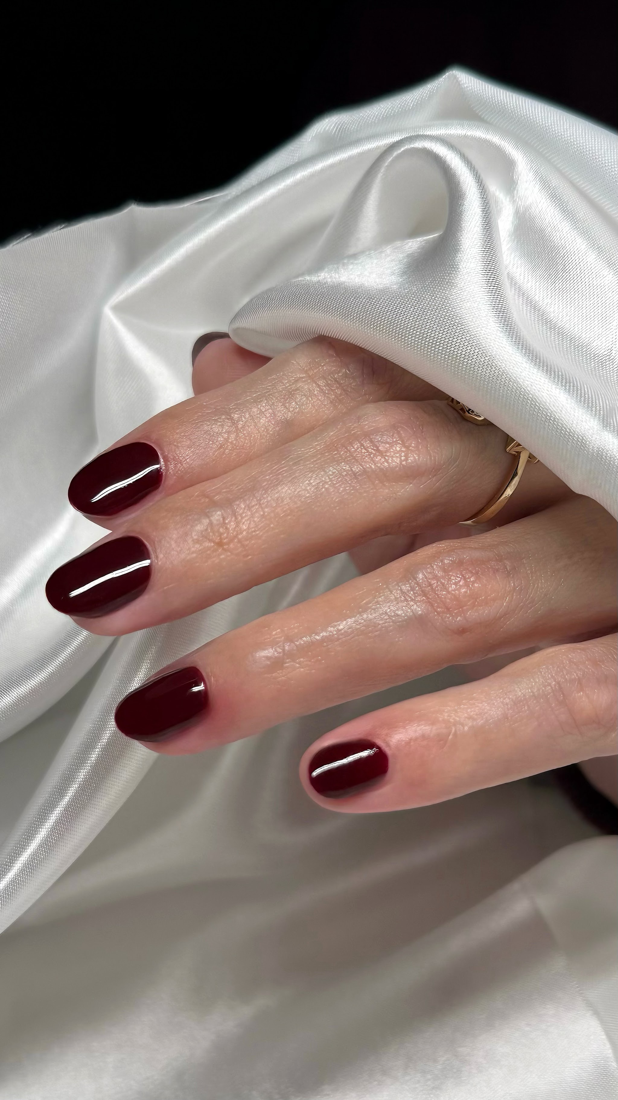 Diep bordeaux gelakte nagels op wit satijn