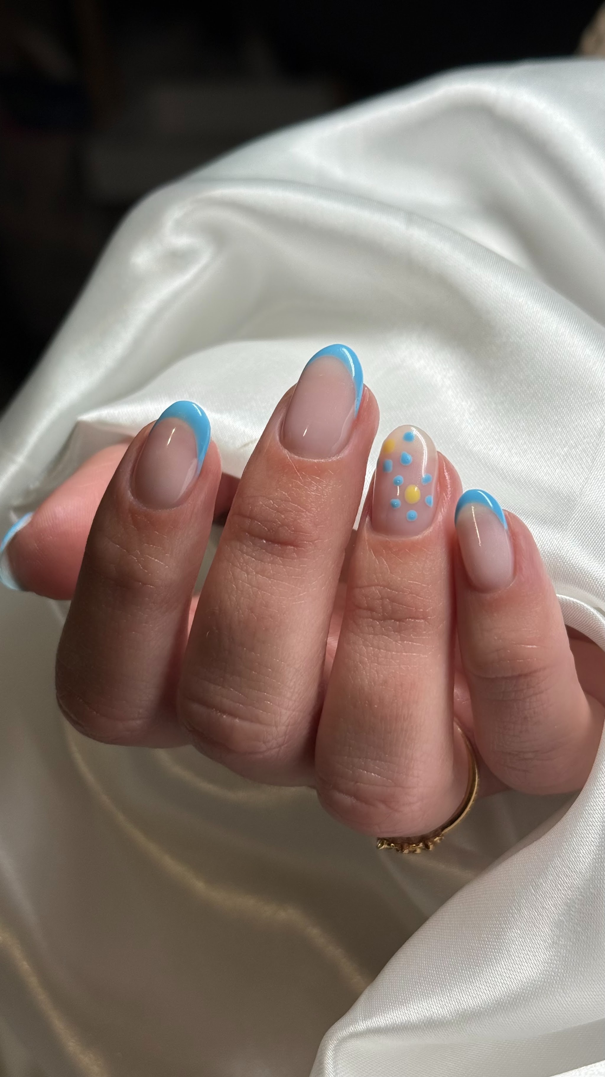 Nude nagels met blauwe French tips en een nagel met nail art
