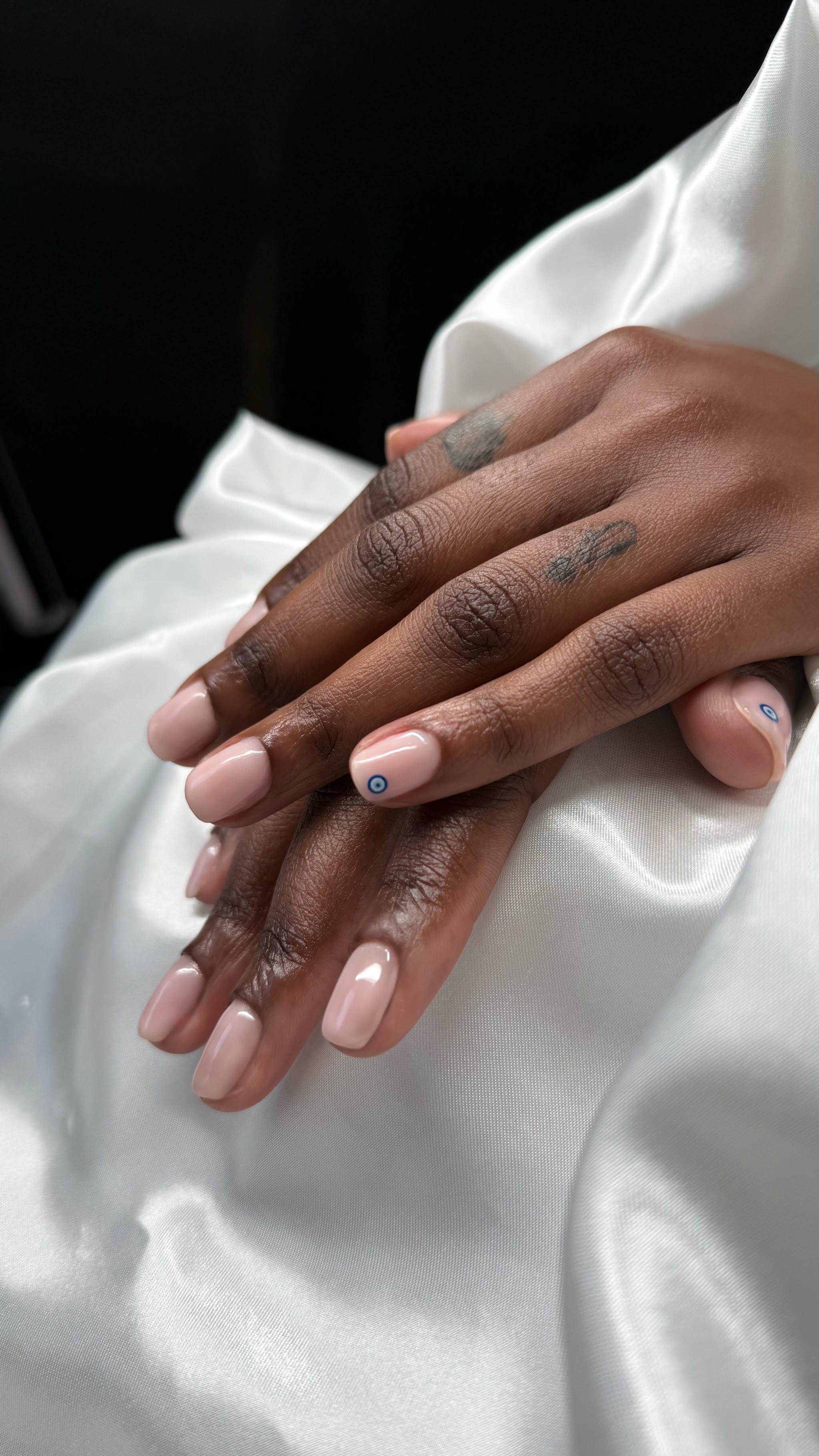 Zachte nude nagels, twee handen op wit satijn